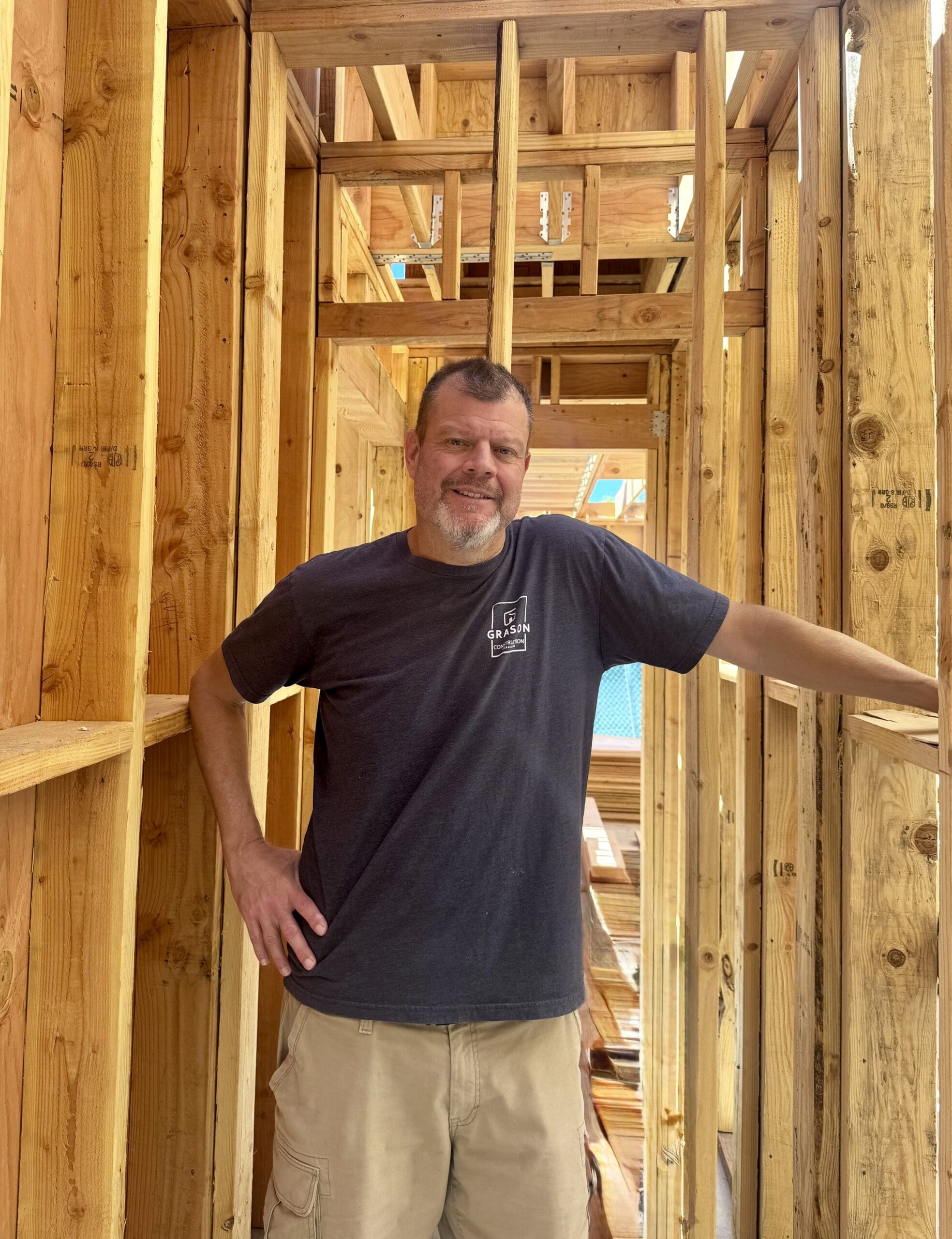 Man smiling inside wooden house framing